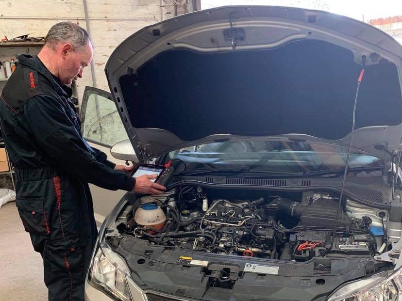 Bruce working under the bonnet of a car.
